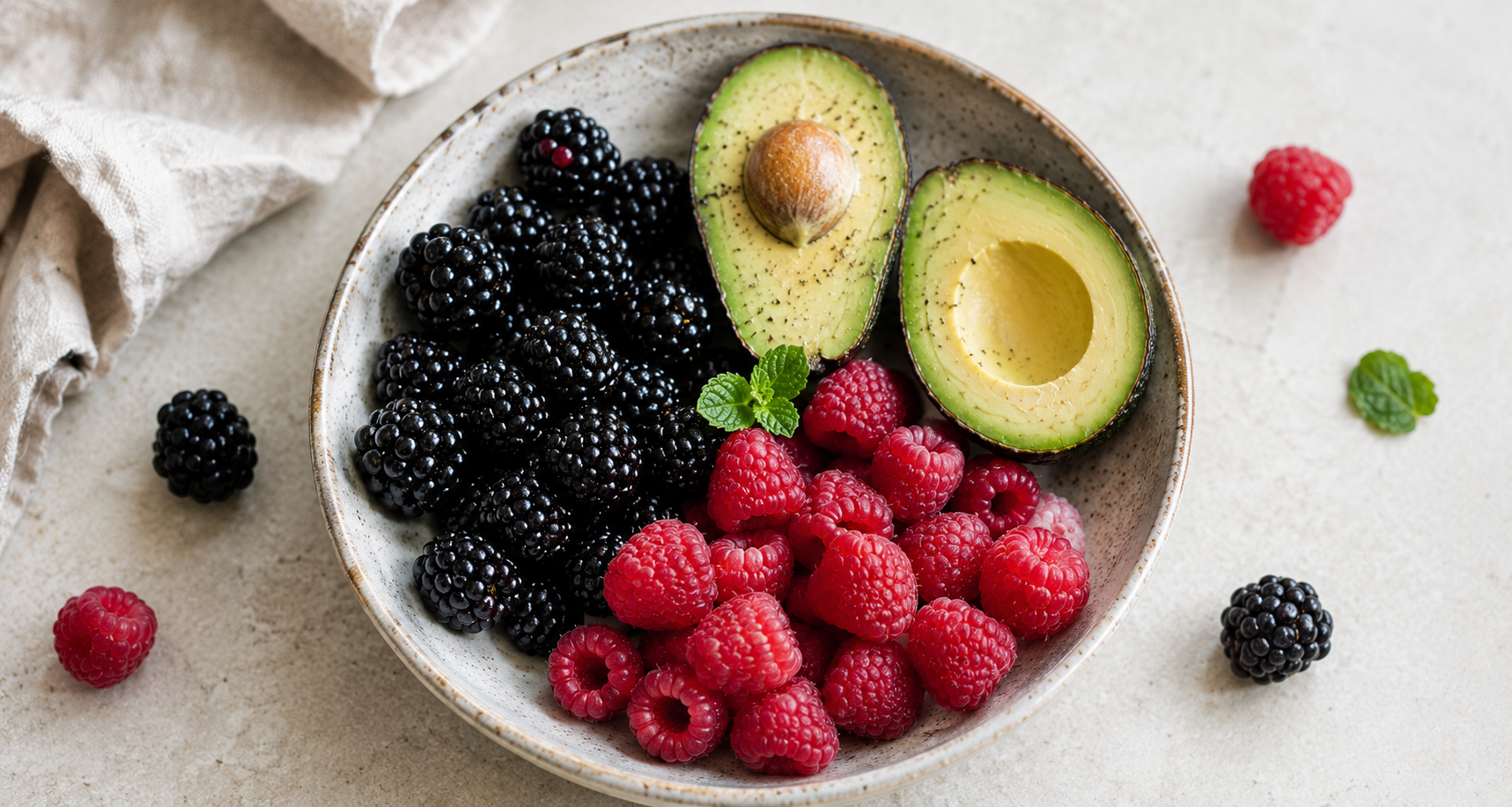 Blackberries, raspberries and a halved avocado in a bowl